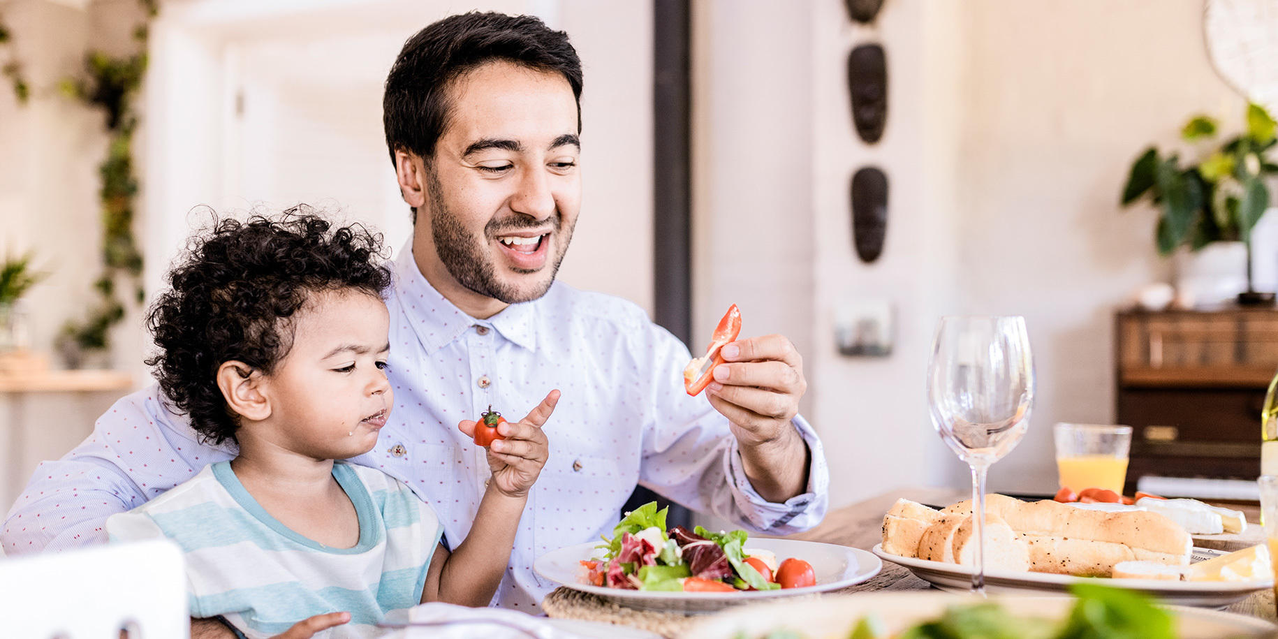 A man and his son enjoying a meal together in a brightly-lit room.