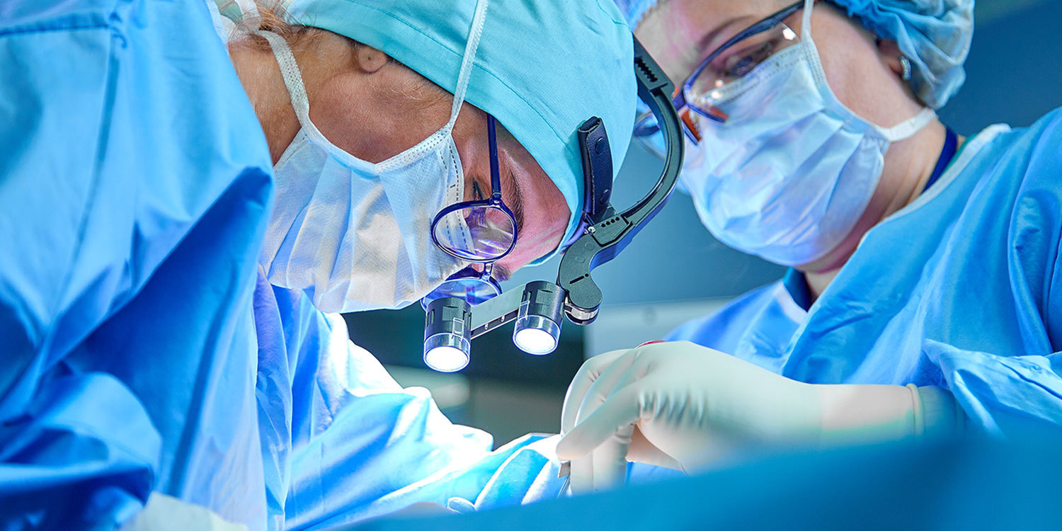 A transplant surgeon and her surgical assistant perform a transplant.