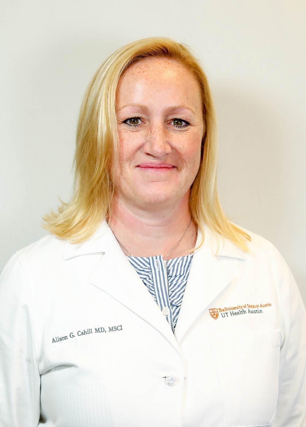 Dr. Alison Cahill wearing a white coat and smiling in front of a white backdrop.