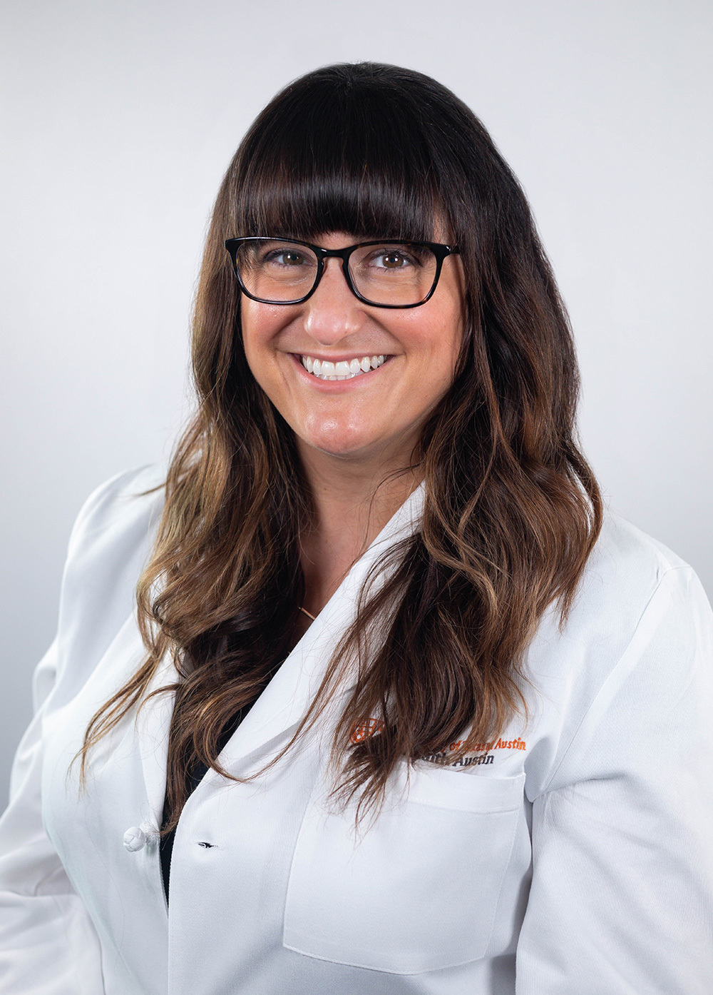 Dr. Amanda Winter-Greenberg wearing a white coat and smiling in front of a white backdrop.