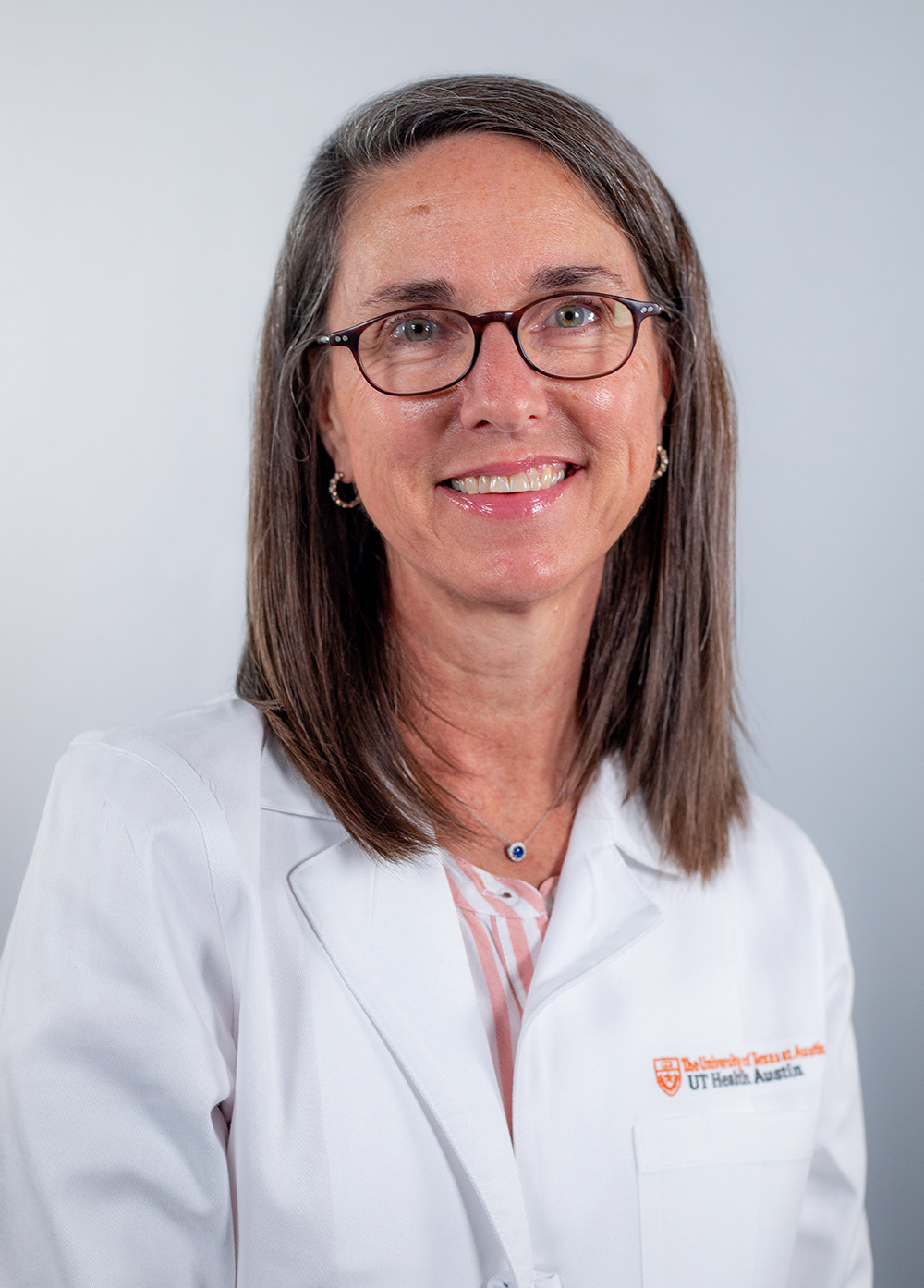 Amy Hemingway wearing a white coat and smiling in front of a white backdrop.