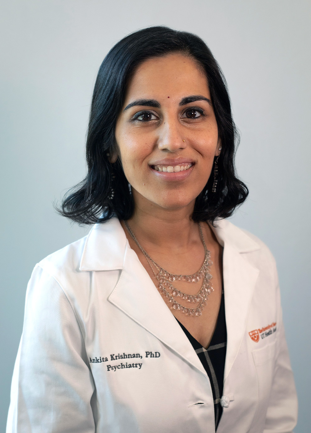 Dr. Ankita Krishnan wearing a white coat and smiling in front of a white backdrop.