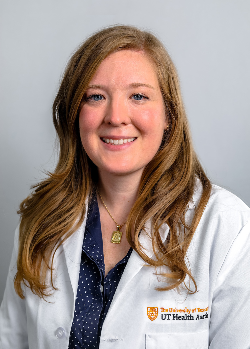 Anna Brauninger wearing a white coat and smiling in front of a white backdrop.