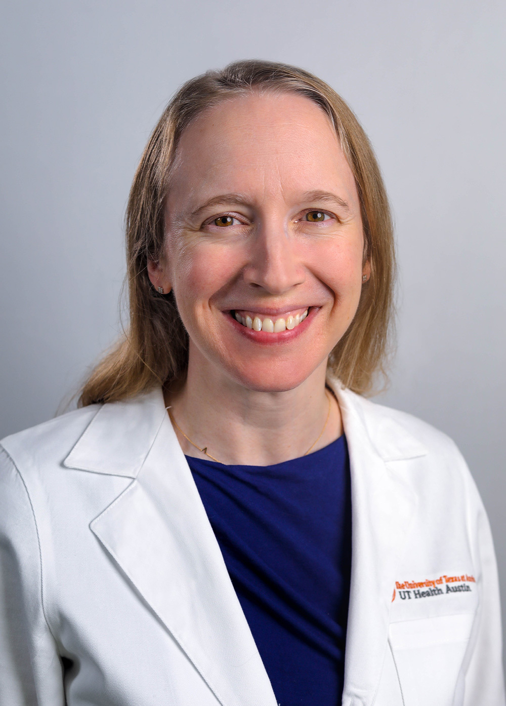 Dr. Audrey Brumback wearing a white coat and smiling in front of a white backdrop.