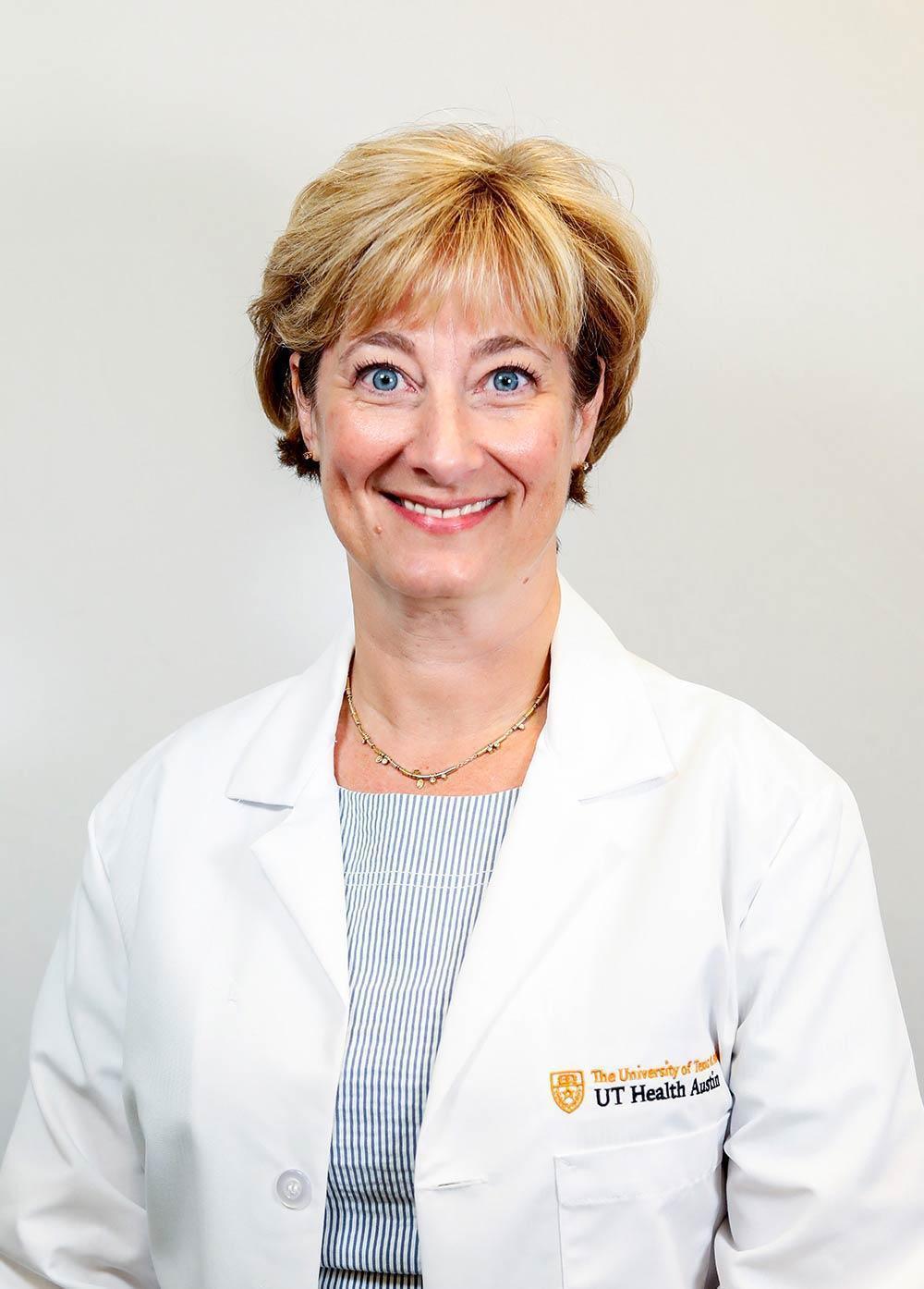 Dr. Celeste Sheppard wearing a white coat and smiling in front of a white backdrop.
