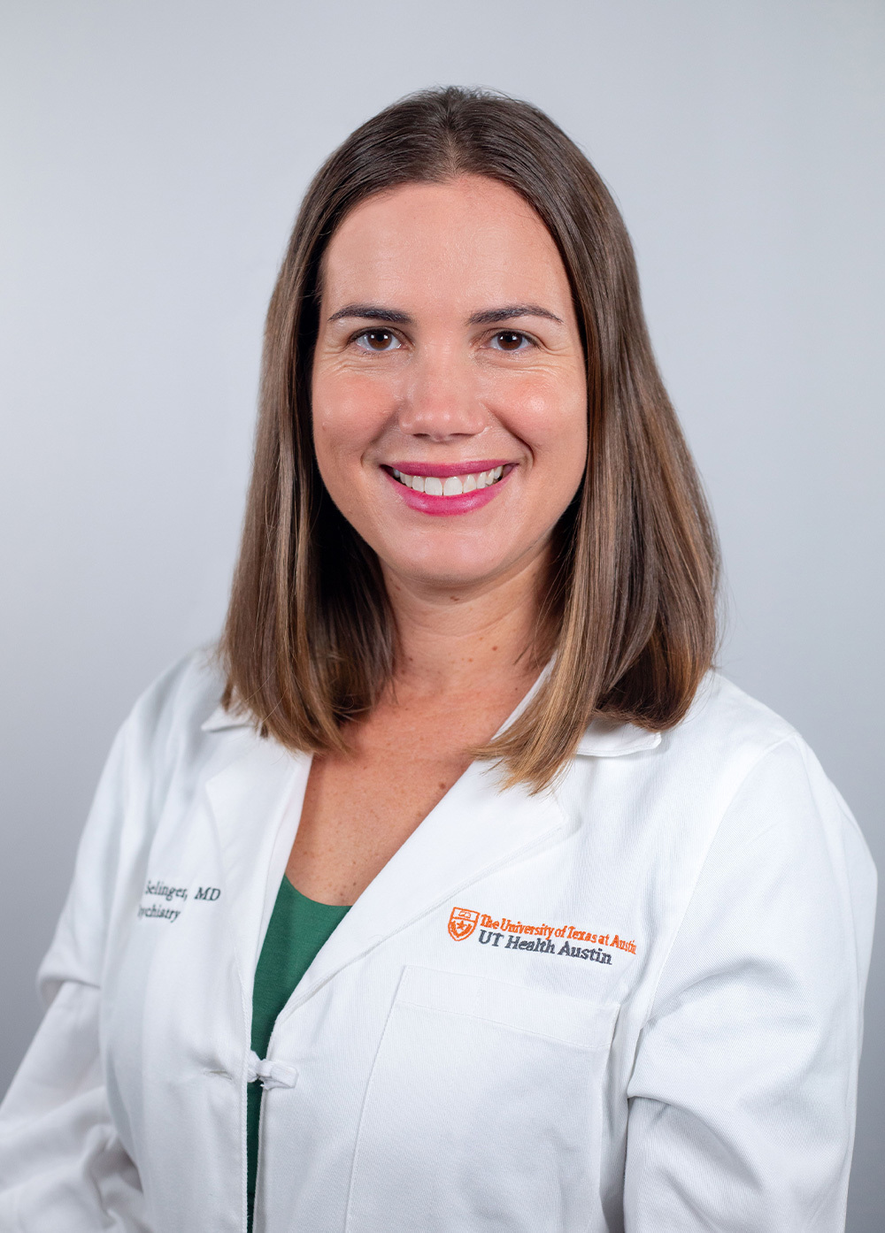 Dr. Claire Selinger wearing a white coat and smiling in front of a white backdrop.