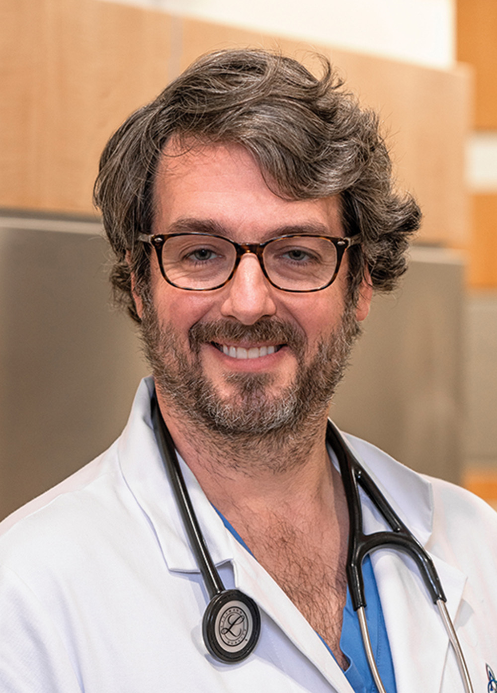 Dr. Clay A. Cauthen wearing a white coat and stethoscope and smiling indoors.