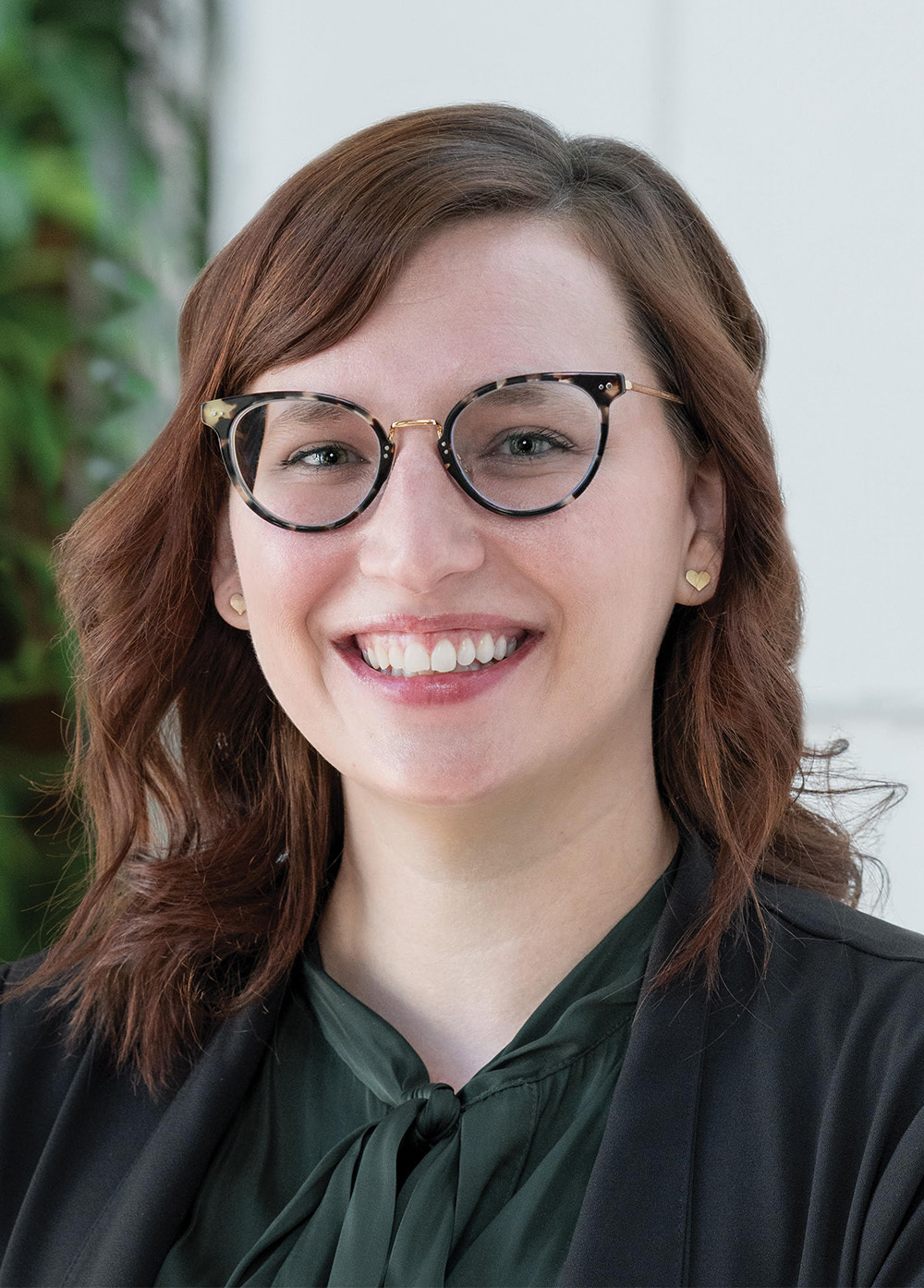 Pediatric Neuroscience Surgery Program Coordinator Courtney Keene Hombroek, BSN, RN, CPN, smiling and wearing a blazer, green blouse, and glasses.
