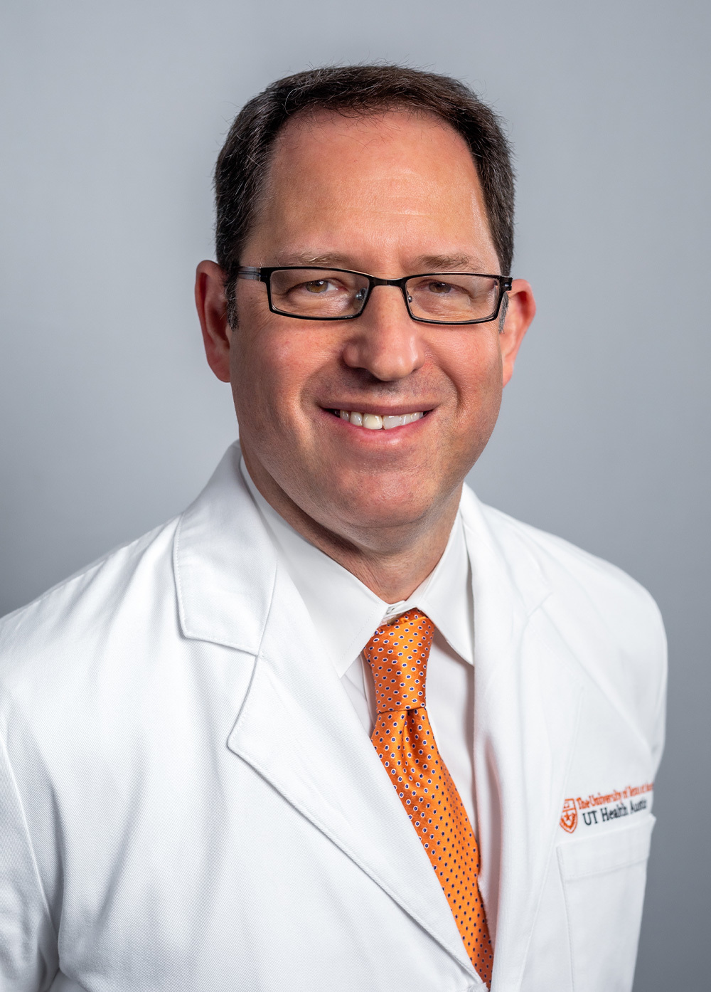 Dr. Daniel Stromberg wearing a white coat and smiling in front of a white backdrop.