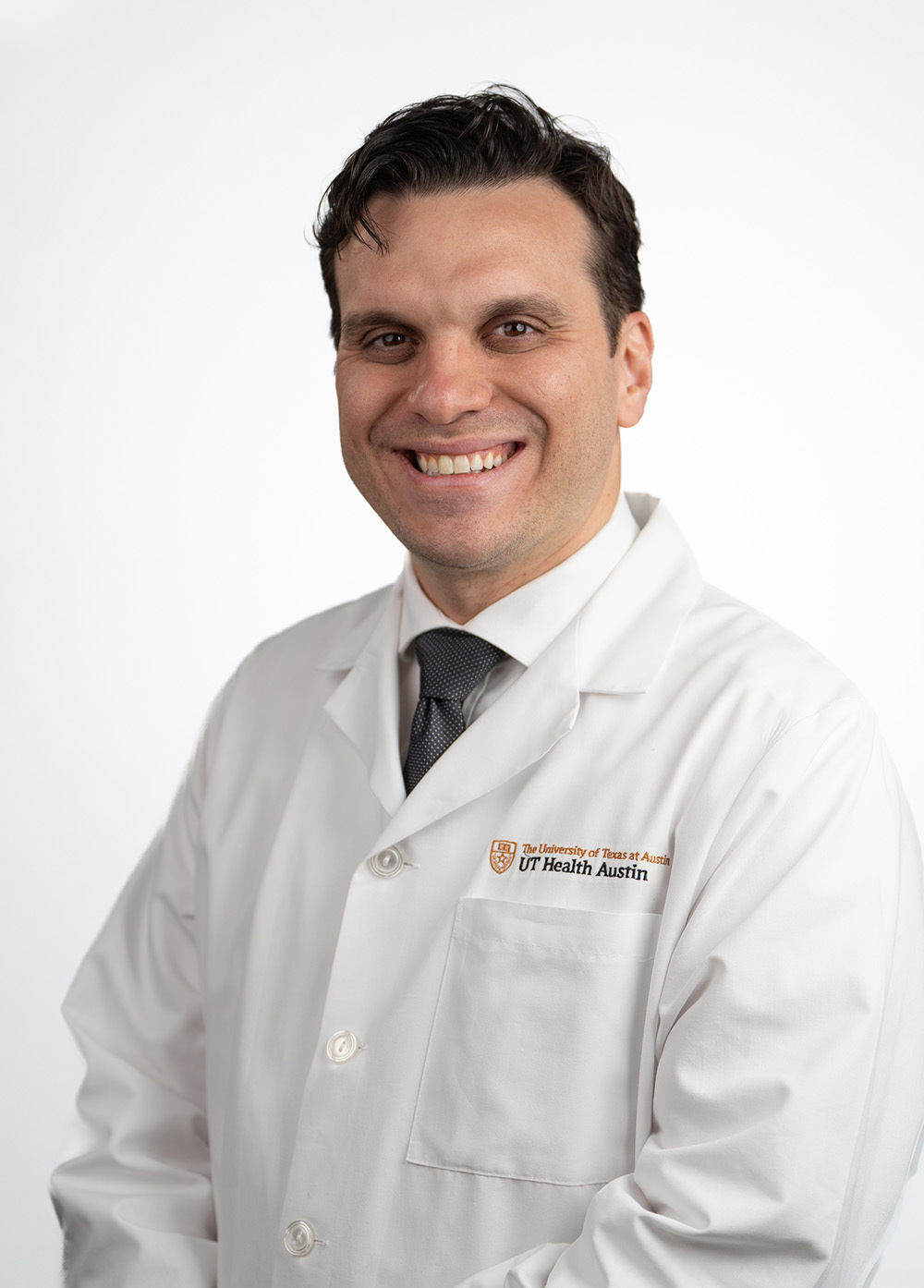 Pediatric cardiologist Davi Tenorio, MD, wearing a white doctor's coat and smiling in front of a white backdrop.