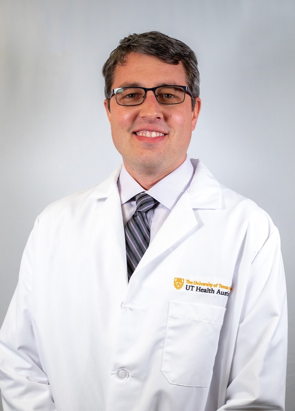 Dr. David Heckler wearing a white coat and smiling in front of a white backdrop.
