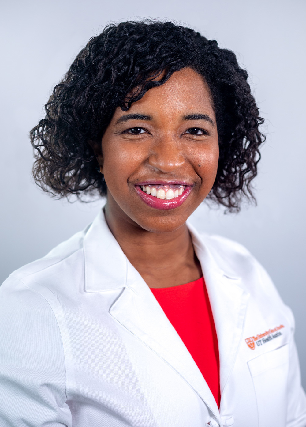 Dr. Denise Johnson wearing a white coat and smiling in front of a white backdrop.