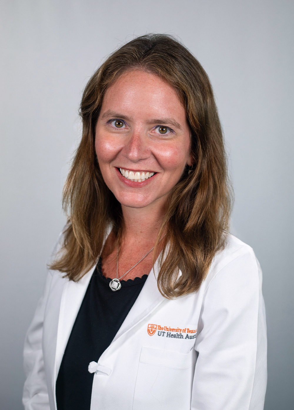 Dr. Emily Greenspahn wearing a white coat and smiling in front of a white backdrop.