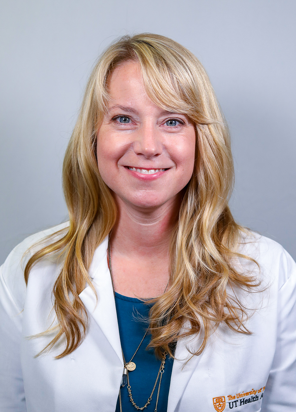 Janet Wilson wearing a white coat and smiling in front of a white backdrop.