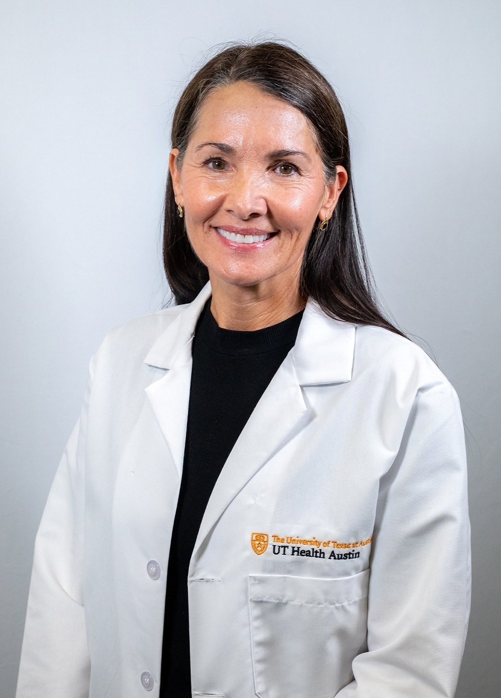 Dr. Janie Black wearing a white coat and smiling in front of a white backdrop.