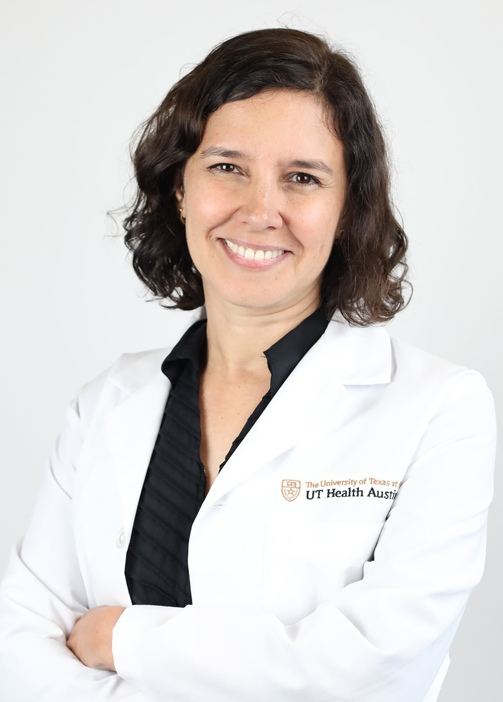 Dr. Jennifer Aranda wearing a white coat and smiling in front of a white backdrop.