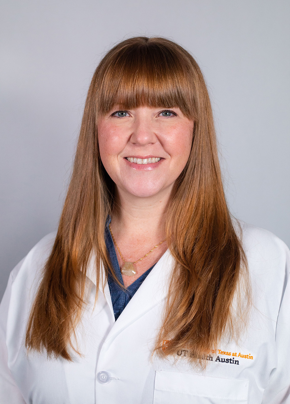 Jennifer Farley wearing a white coat and smiling in front of a white backdrop.