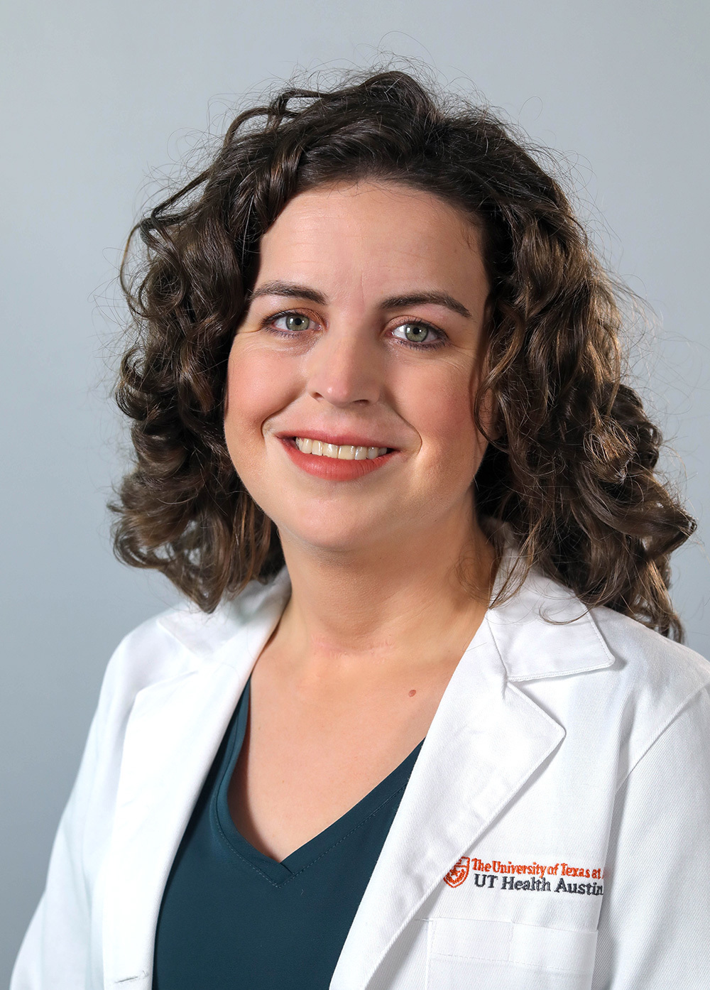 Pediatric neuropsychologist Jessica Pliego, PhD, wearing a white coat and smiling in front of a white backdrop.