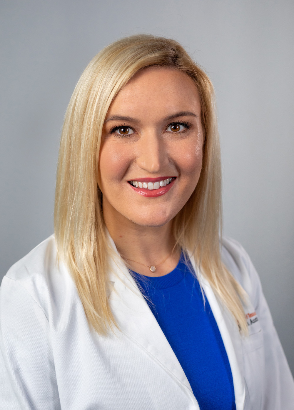 Dr. Lindsay Wood wearing a white coat and smiling in front of a white background.