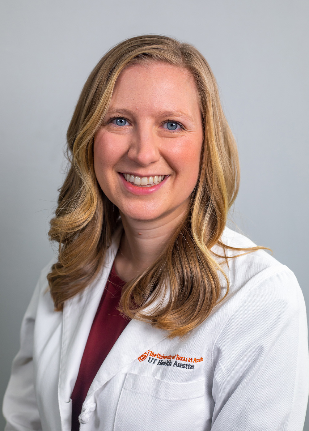 Dr. Lindsey Elliott wearing a white coat and smiling in front of a white backdrop.
