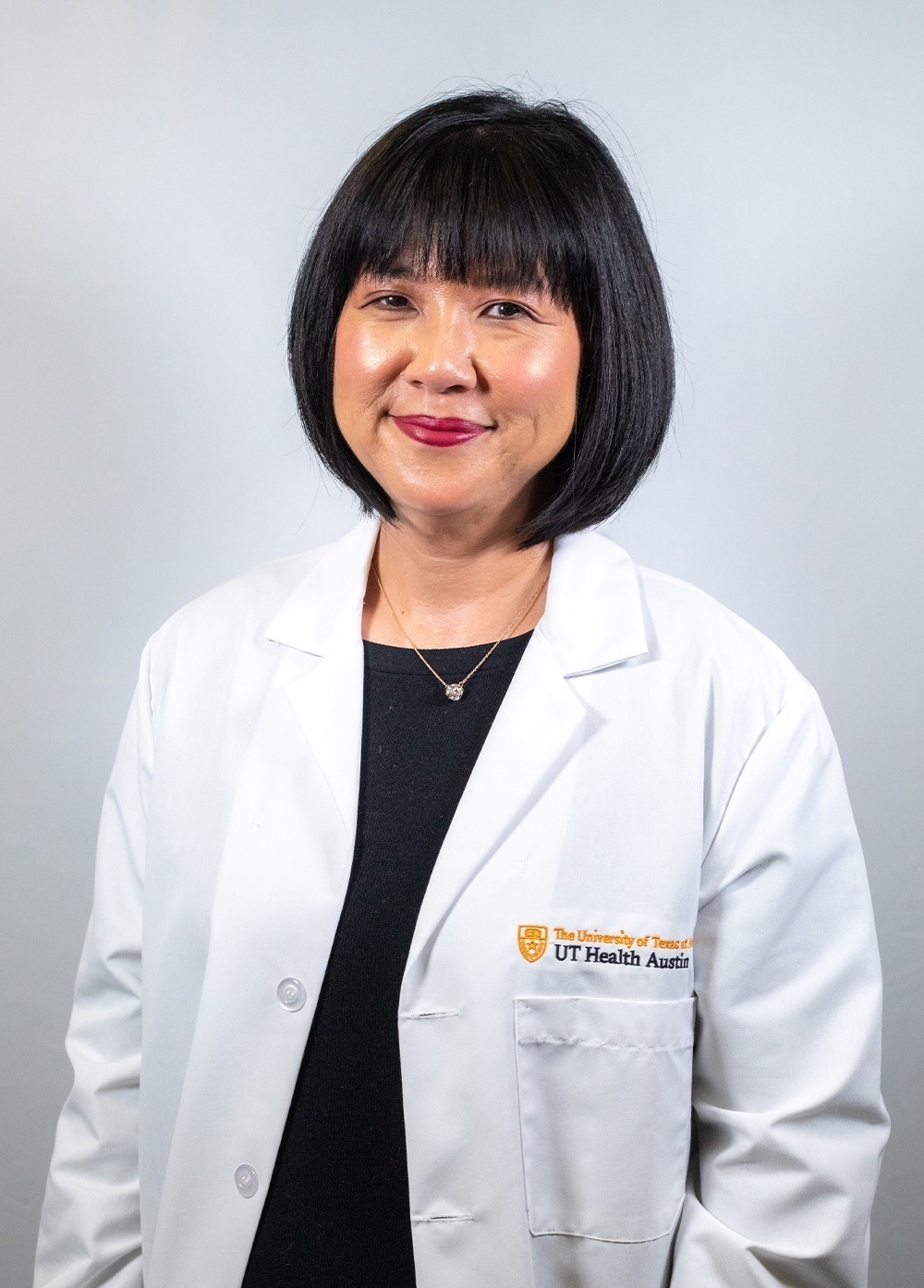Dr. Lynn Monnat wearing a white coat and smiling and smiling in front of a white backdrop.