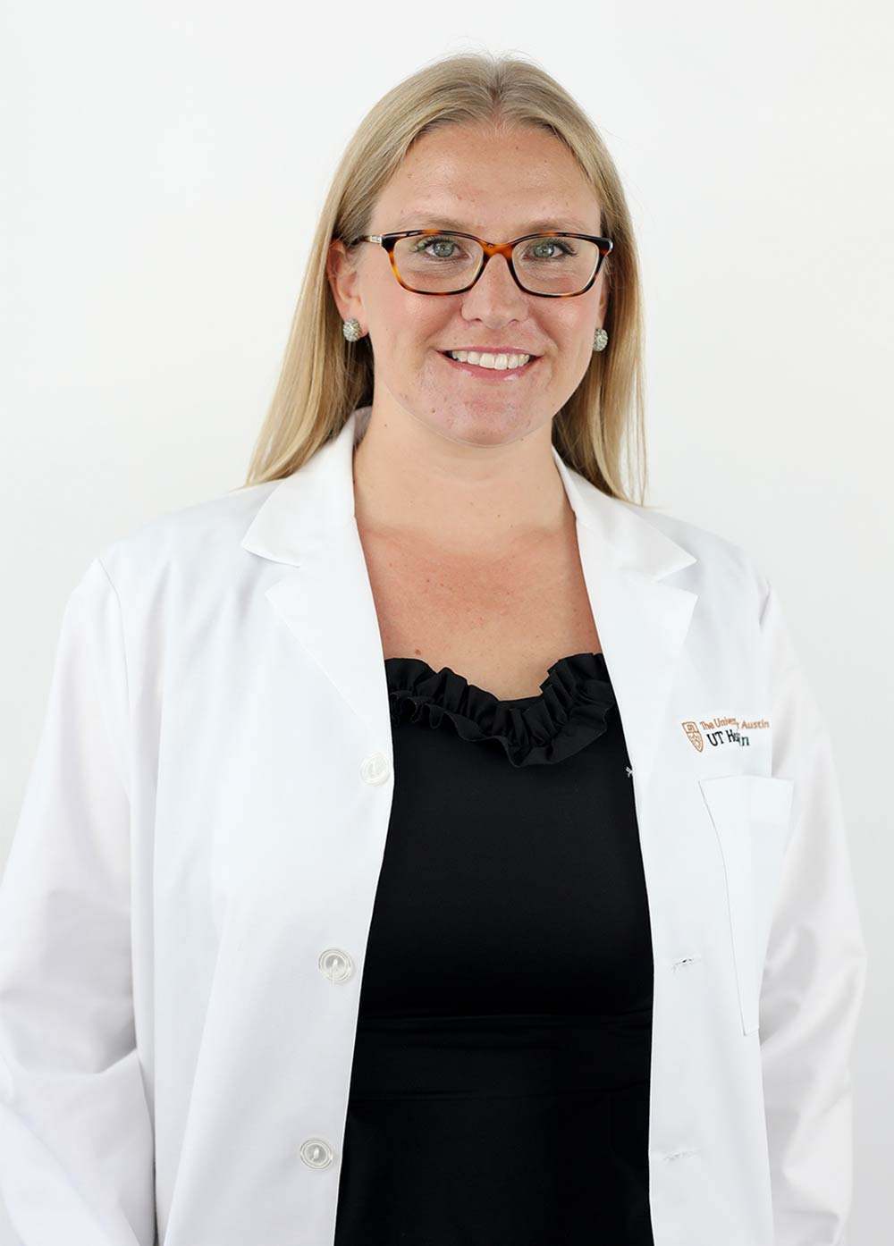 Dr. Margaret Whitney wearing a white coat and smiling in front of a white backdrop.