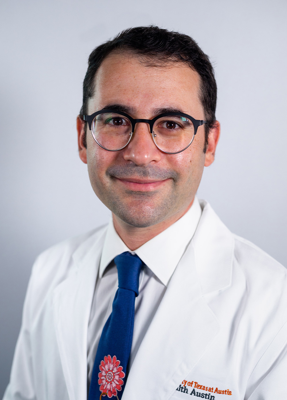 Dr. Max Holtz wearing a white coat and smiling in front of a white backdrop.