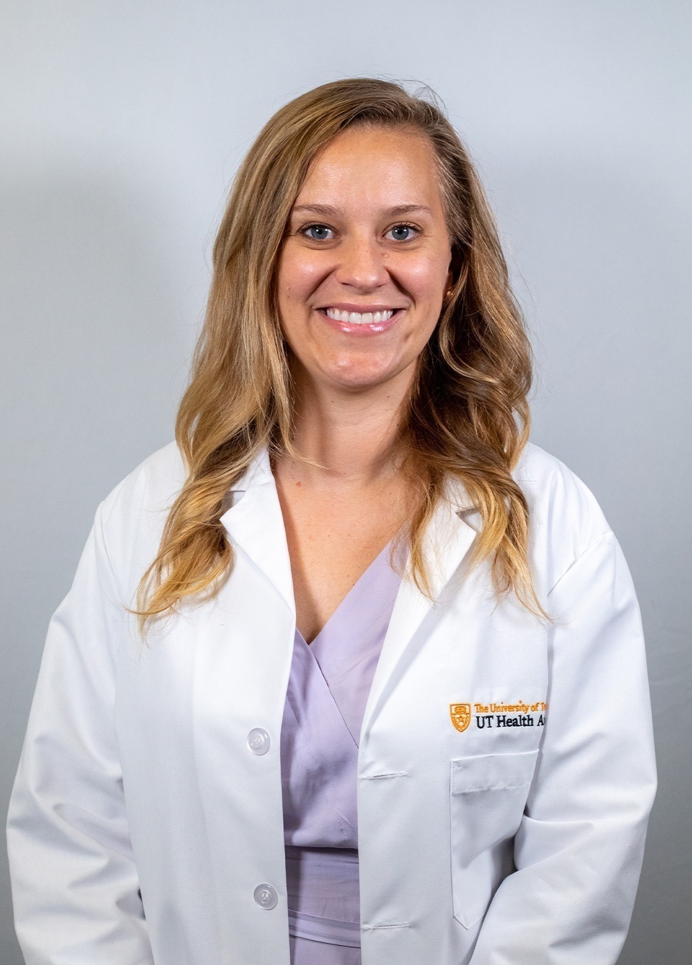 Dr. Meredith Brinster wearing a white coat and smiling in front of a white backdrop.
