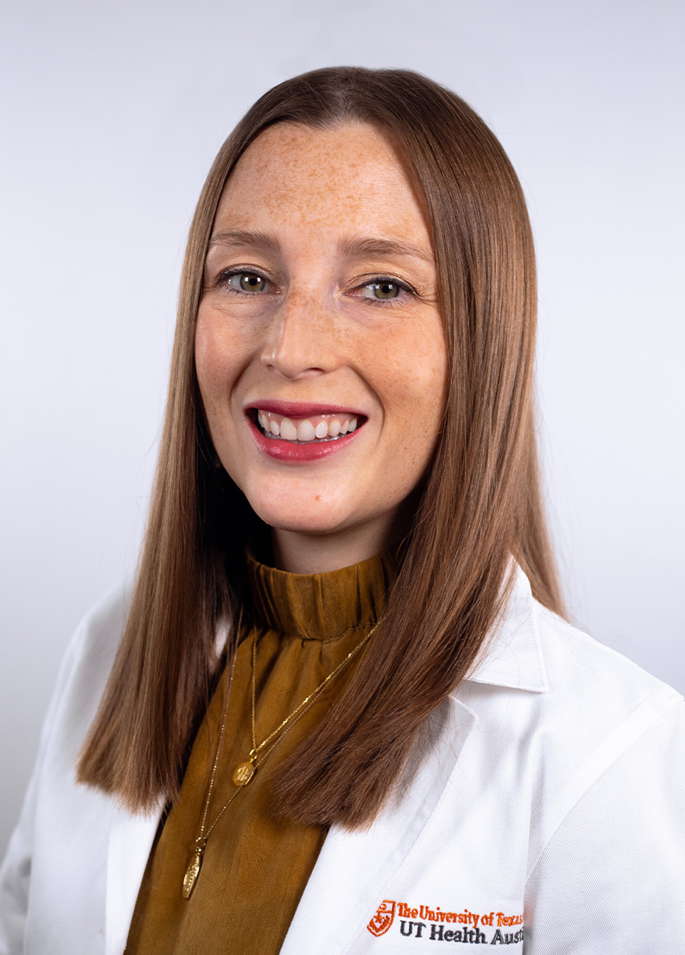 Olivia P. Martino wearing a white coat and smiling in front of a white backdrop.