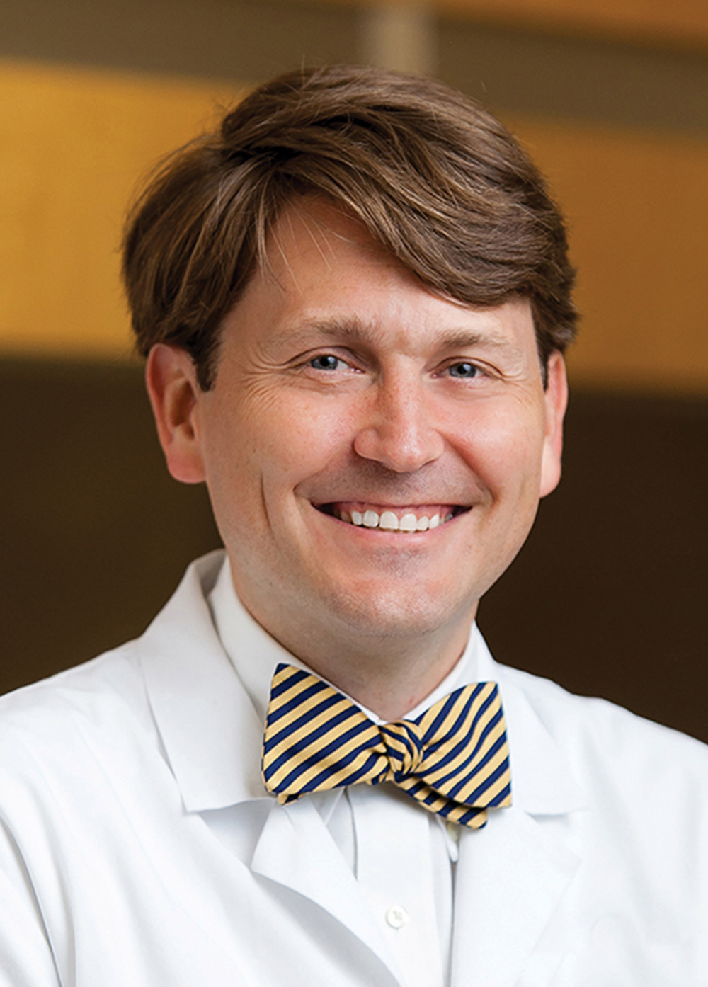 Dr. Raymond E. Bietry wearing a white coat and patterned bow tie and smiling indoors.