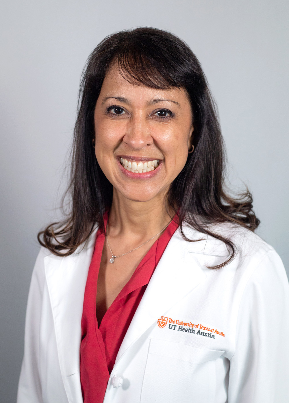 Pediatric neuropsychologist Rosario DeLeon, PhD, wearing a white coat and smiling in front of a white backdrop.
