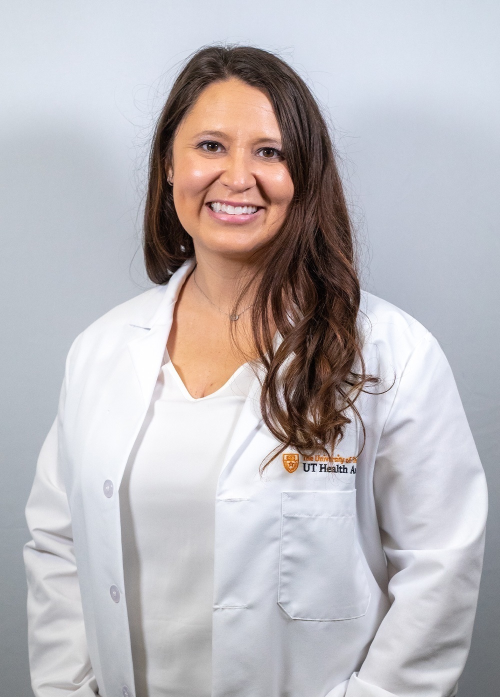Dr. Sasha Jaquez wearing a white coat and smiling in front of a white backdrop.