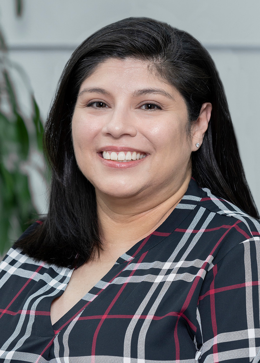 Social worker Suzanne Pekarek, LMSW, smiling in a plaid shirt. She has shoulder-length dark hair.