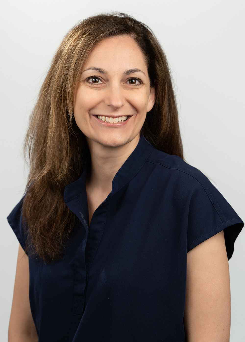 Vanessa Silva wearing a dark blouse and smiling in front of a white backdrop.