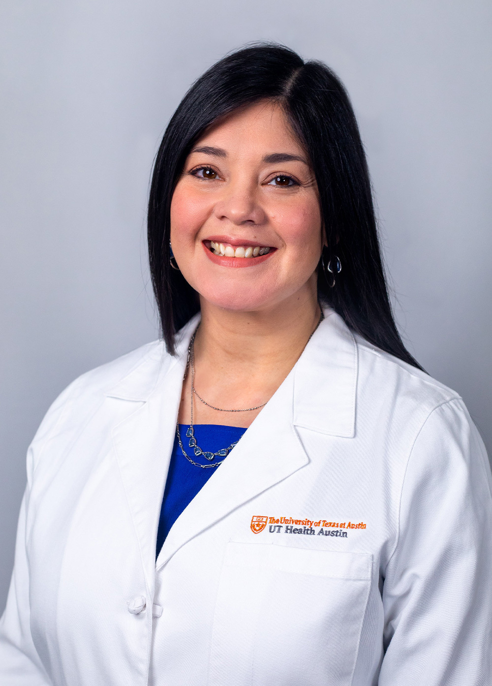 Ligiola Aranaga Sanchez wearing a white coat and smiling in front of a white backdrop.