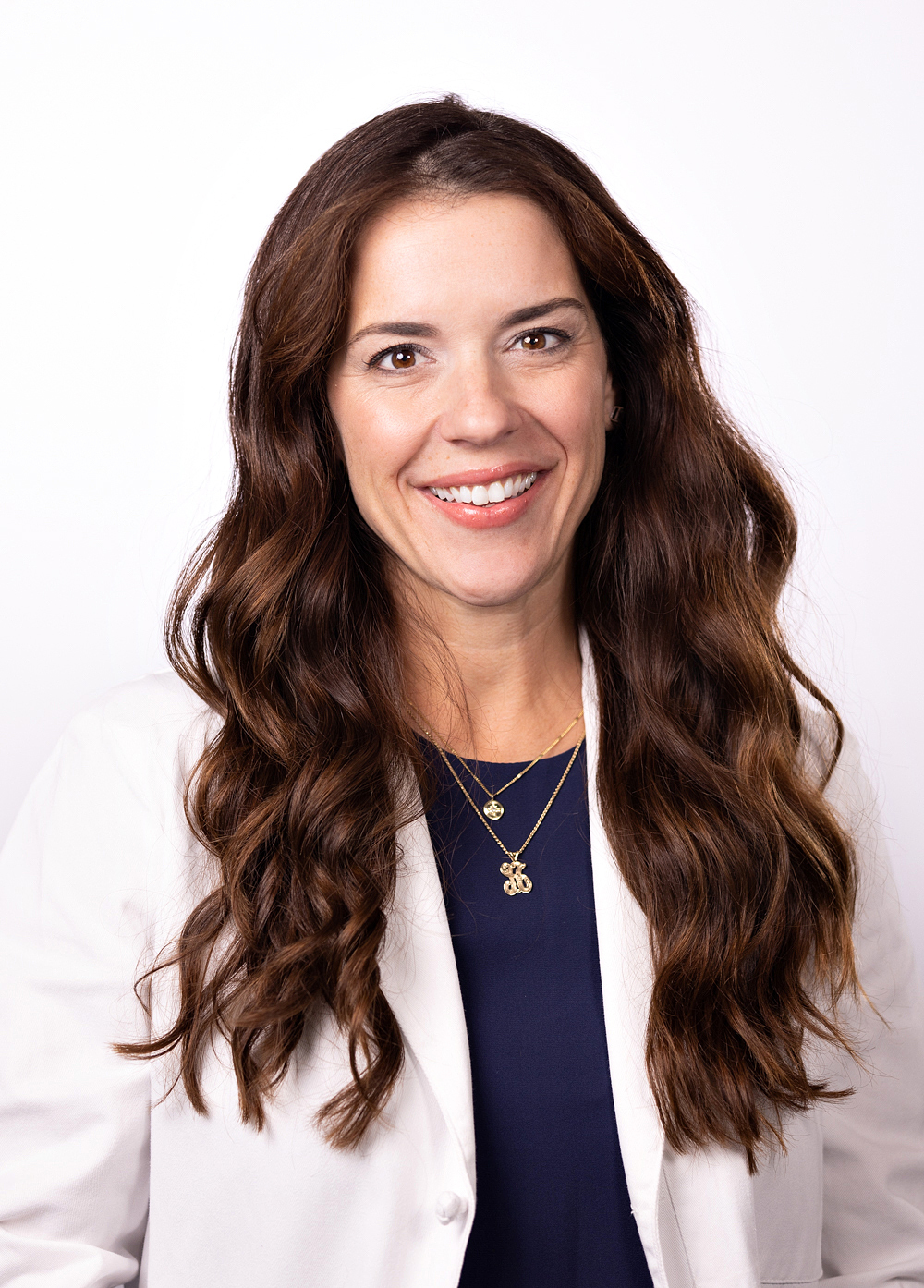 Amanda Balch wearing a white coat and smiling in front of a white backdrop.