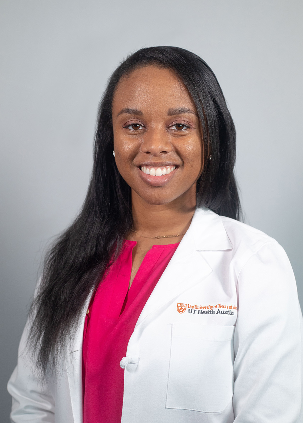 Ashley Griffin wearing a white coat and smiling in front of a white backdrop.
