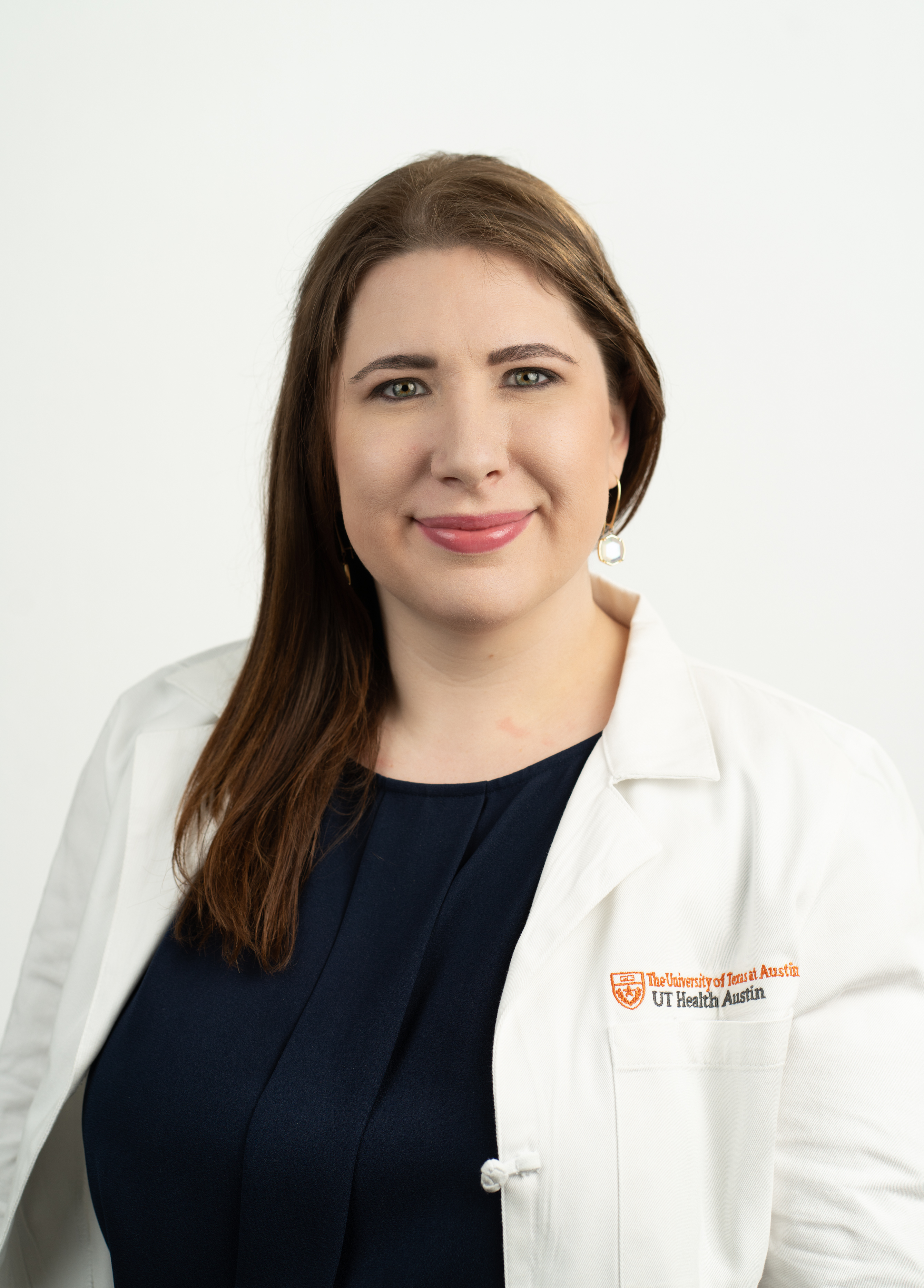 Chelsea Ortman, MD stands in front of a white background smiling.