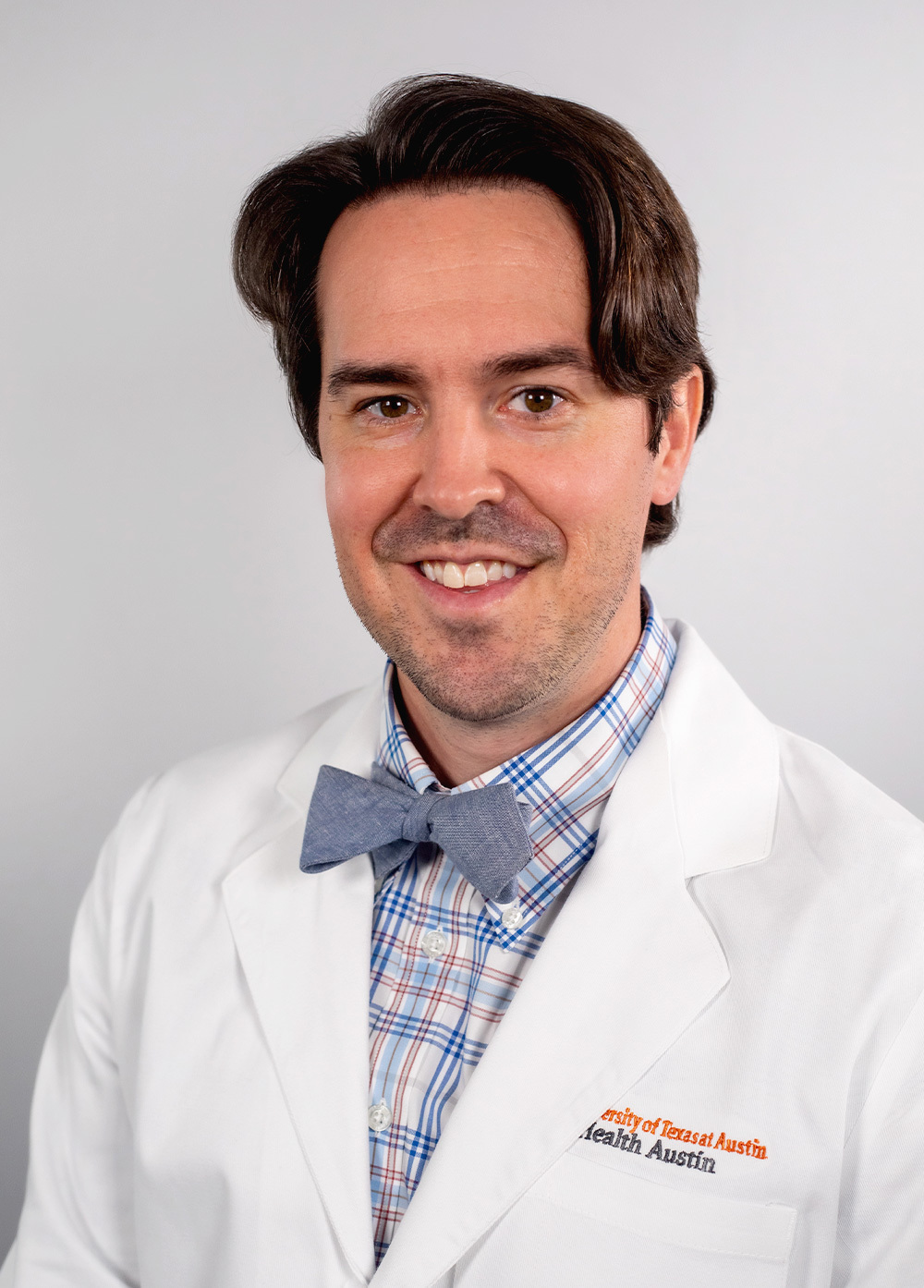 Dr. Clifford Calley wearing a white coat and smiling in front of a white backdrop.