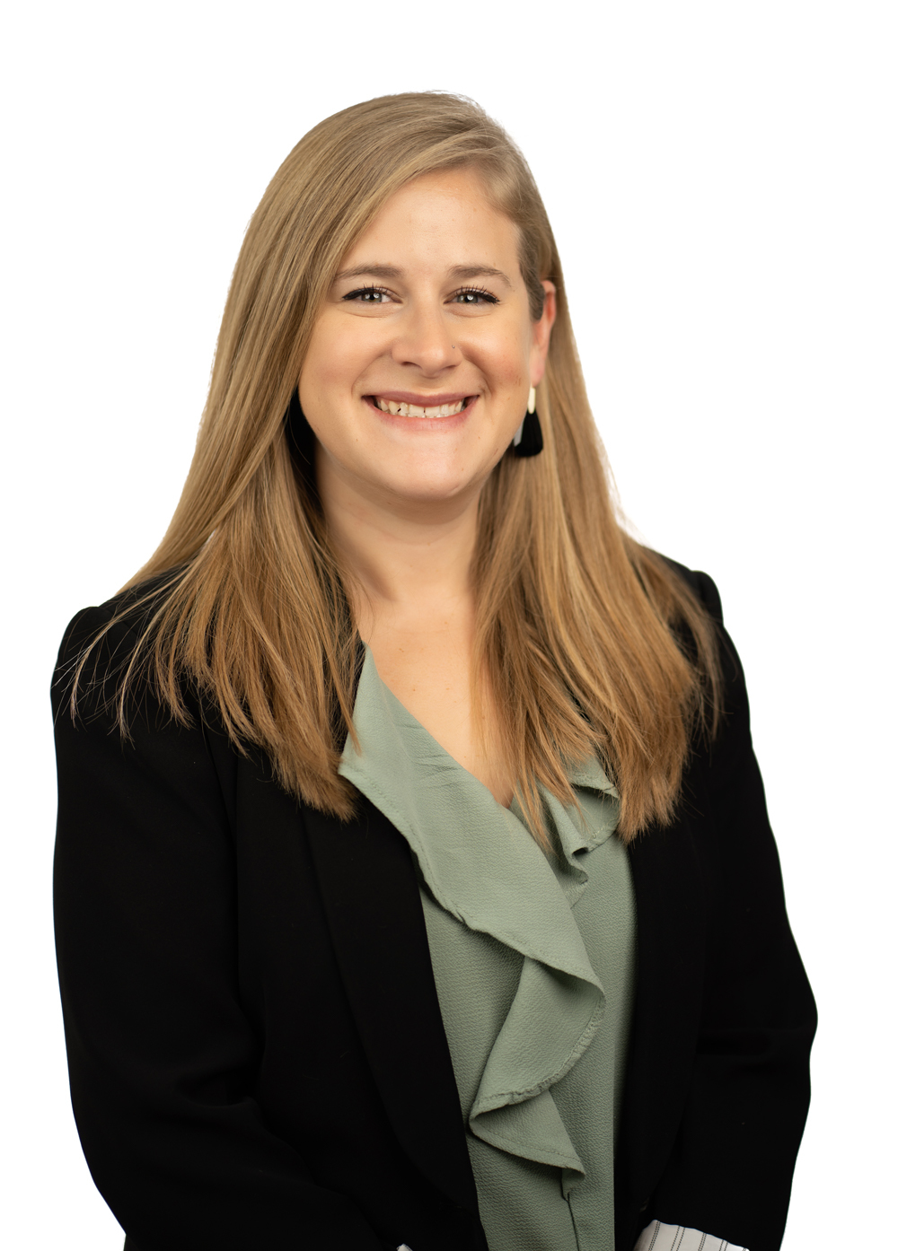 Daniela Boyce wearing a green blouse, black blazer, and smiling in front of a white backdrop.