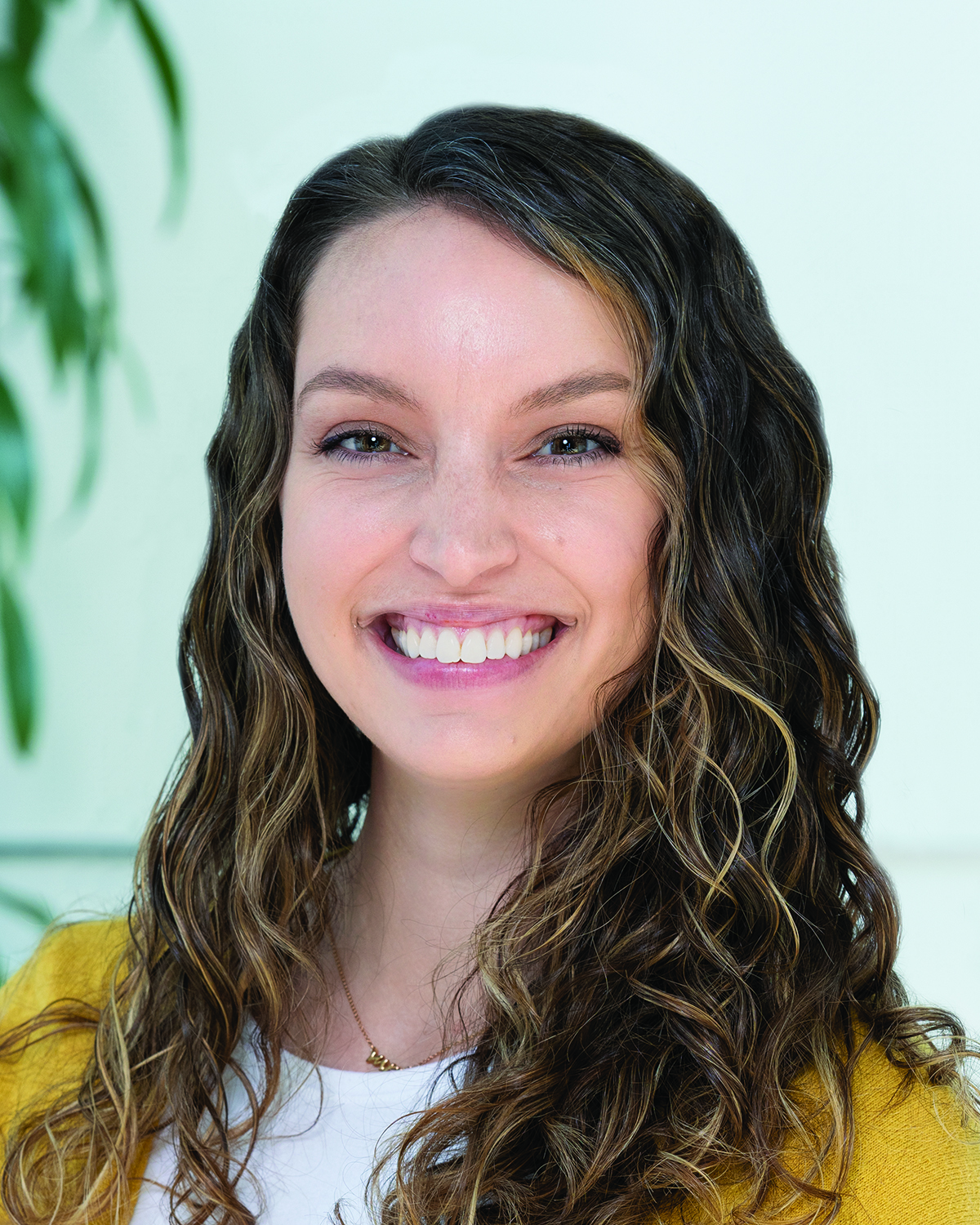 Delaney Herman wearing a yellow cardigan and smiling.