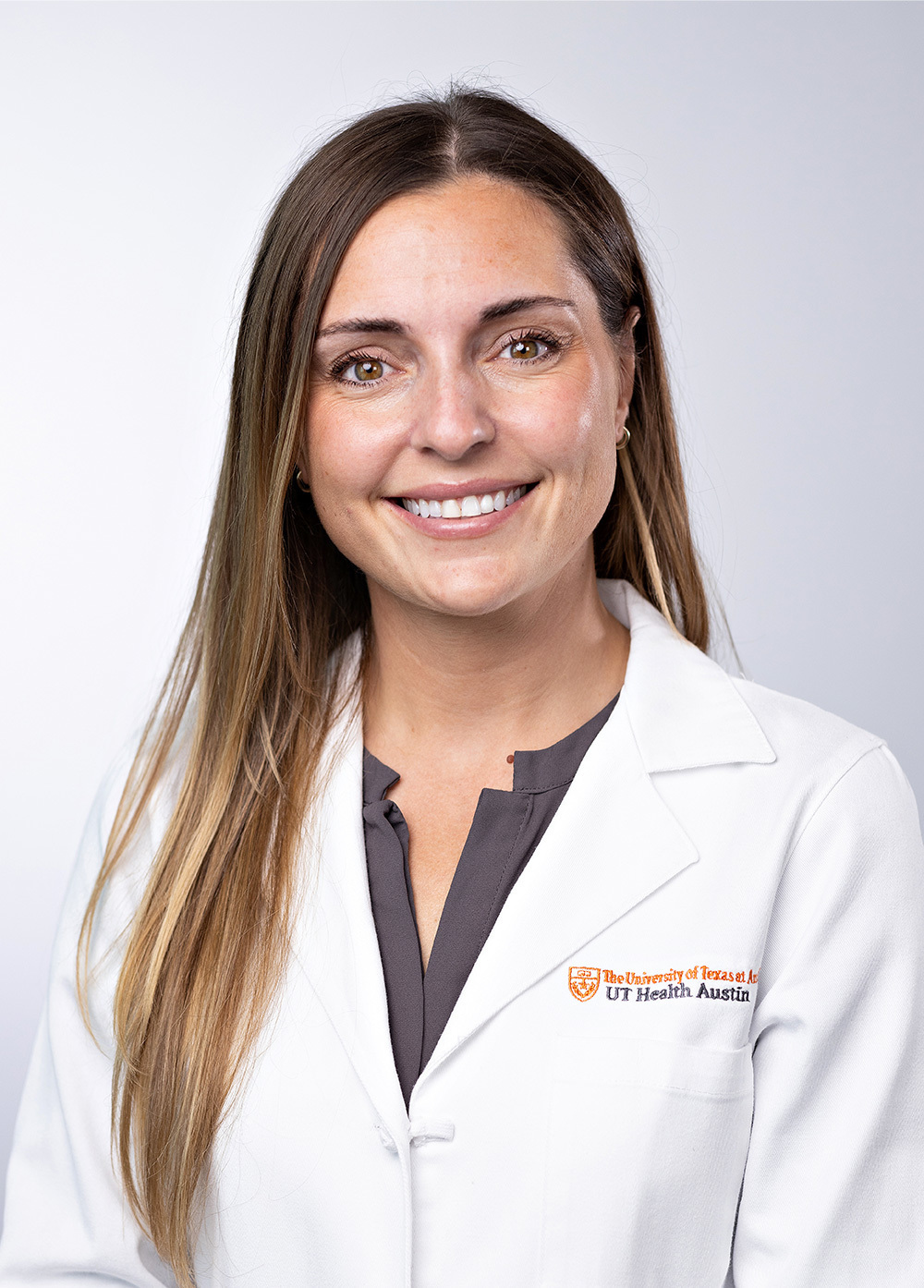 Dr. Elisa Furay wearing a white coat and smiling in front of a white backdrop.
