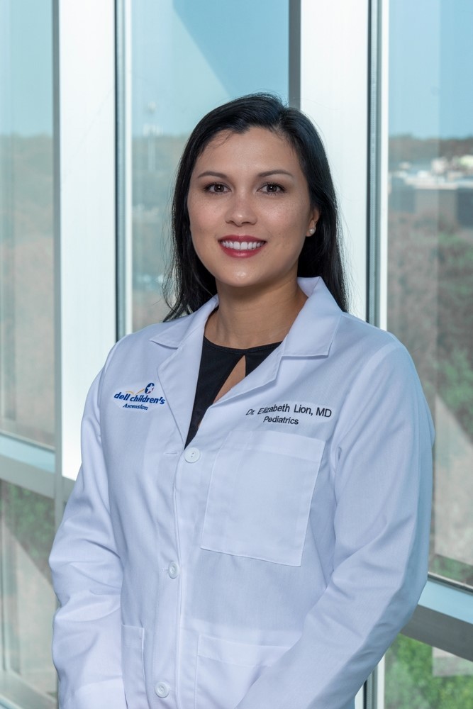 Dr. Elizabeth Lion wearing a white coat and smiling in front of a window.