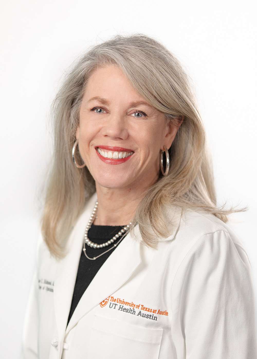 Dr. Jane C. Edmond wearing a white coat and smiling in front of a white backdrop.