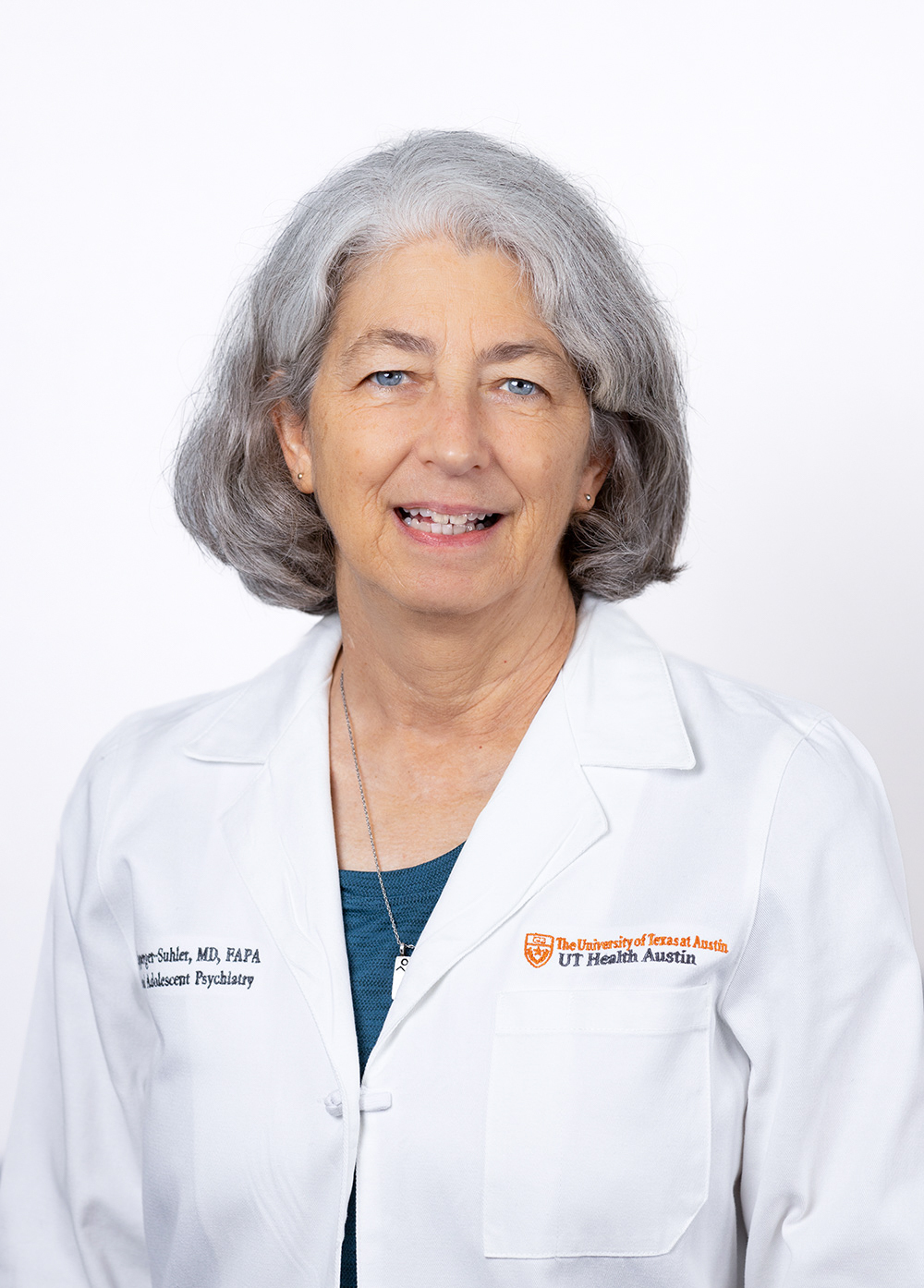 Dr. Jane Ripperger-Suhler is wearing a white coat and smiling in front of a white backdrop.