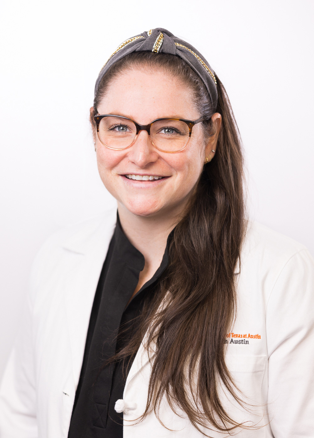 Jennifer Sear wearing a white coat and smiling in front of a white backdrop.