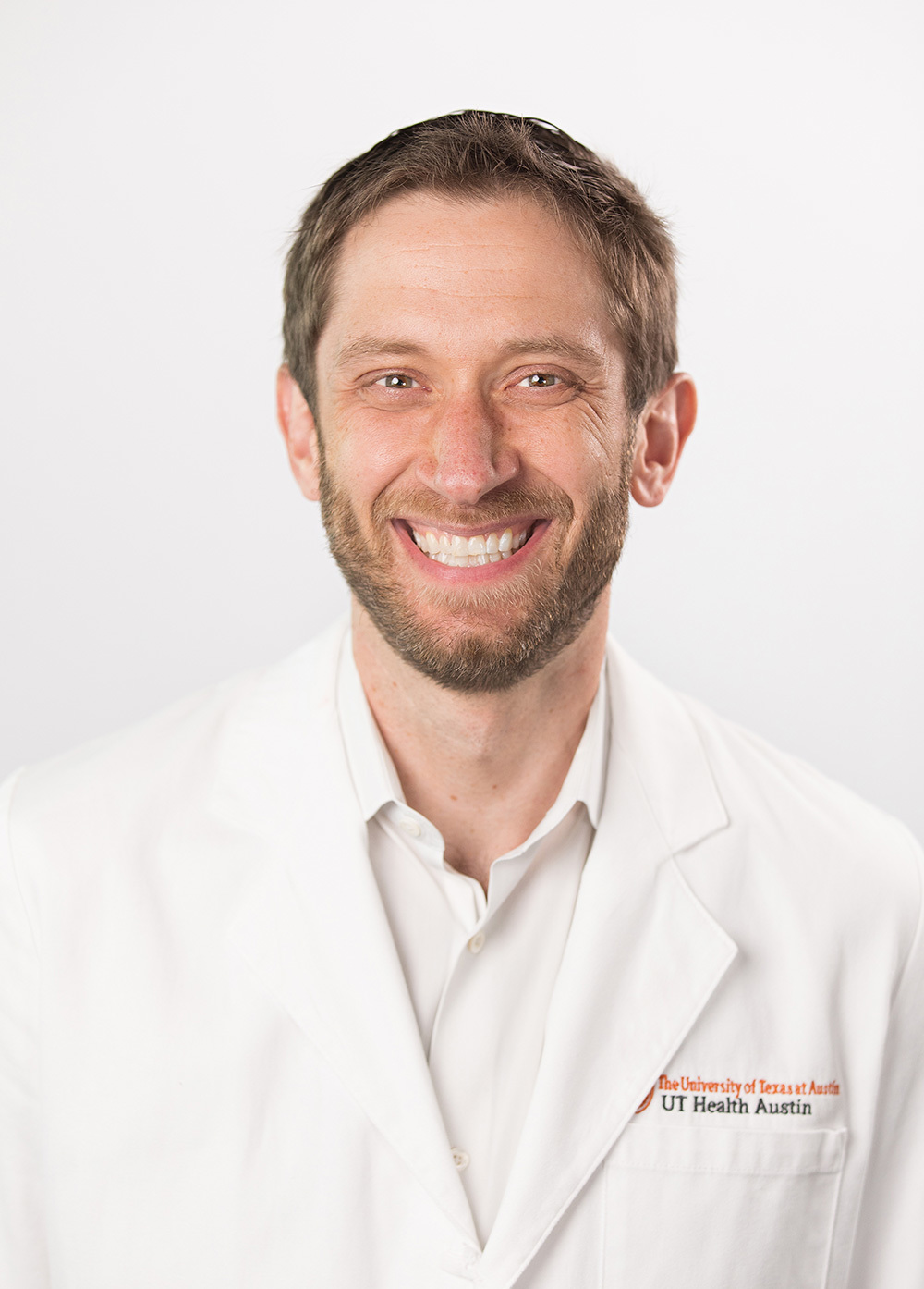 Dr. Joel Adler wearing a white coat and smiling in front of a white backdrop.
