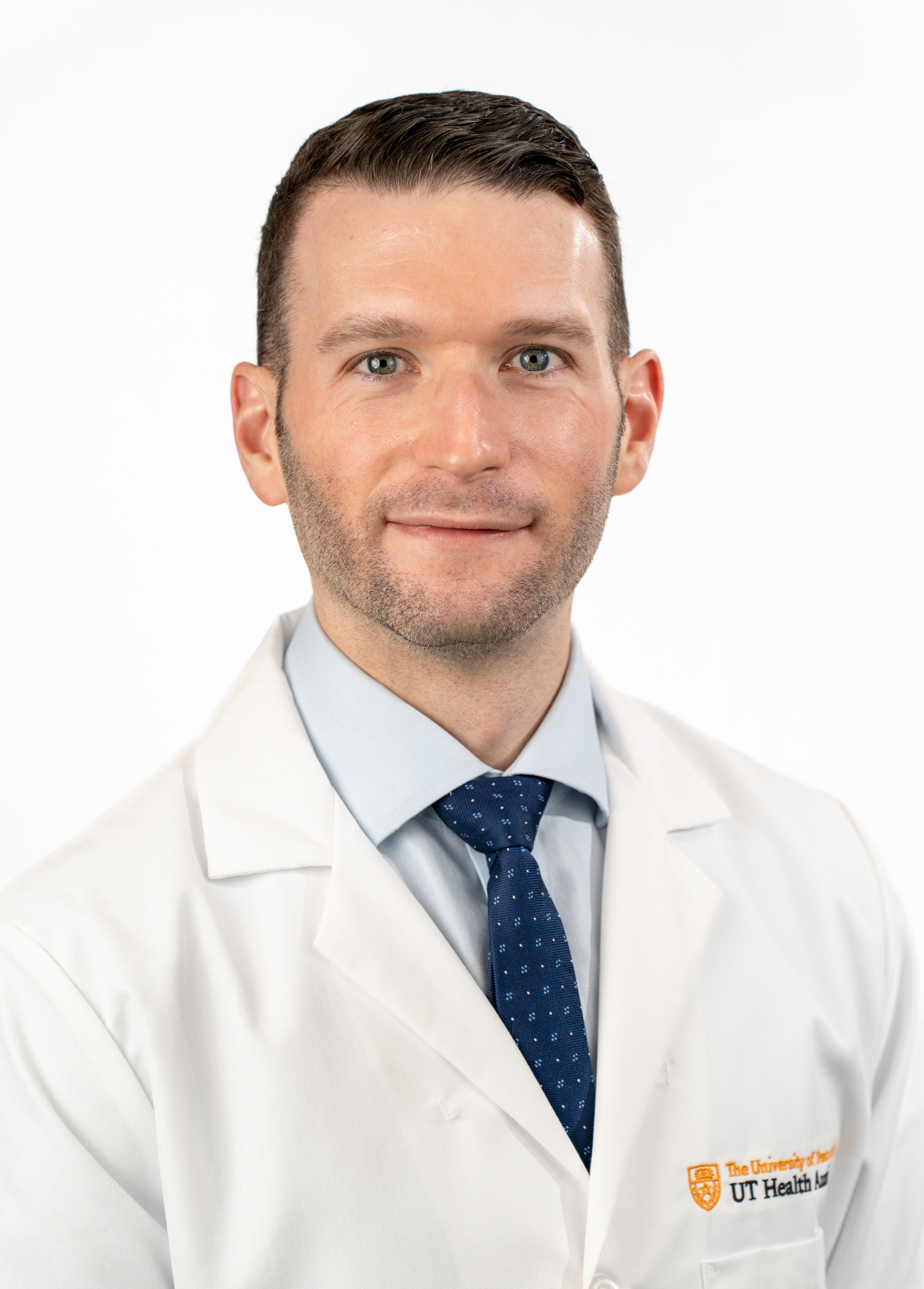 Dr. Joshua Grimm wearing a white coat and smiling in front of a white backdrop.