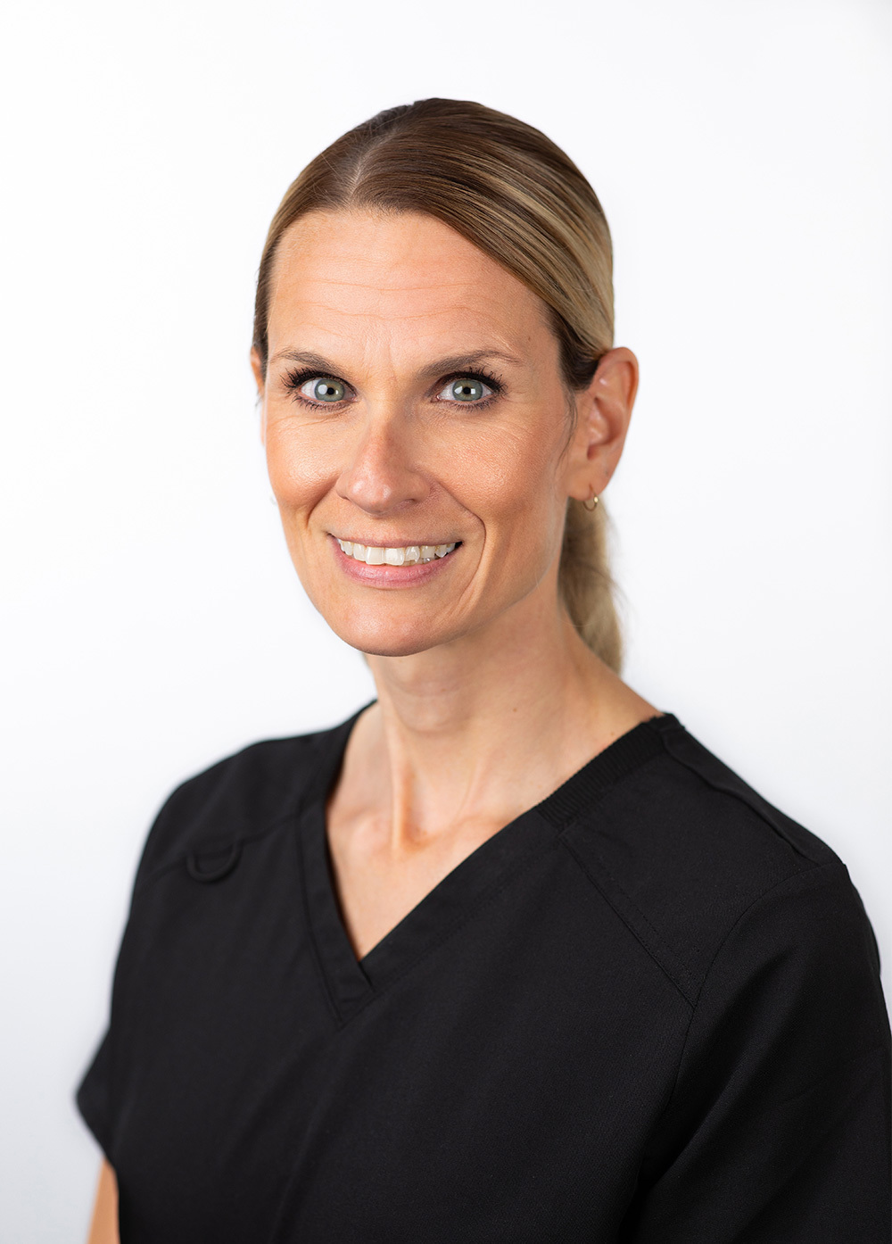 Joy Vanderway wearing dark scrubs and smiling in front of a white backdrop.