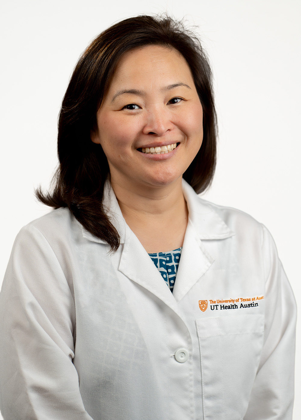 Karen Kim, MD, an adult cardiac surgeon, stands in front of a white backdrop, smiling with a slight tilt to her head.